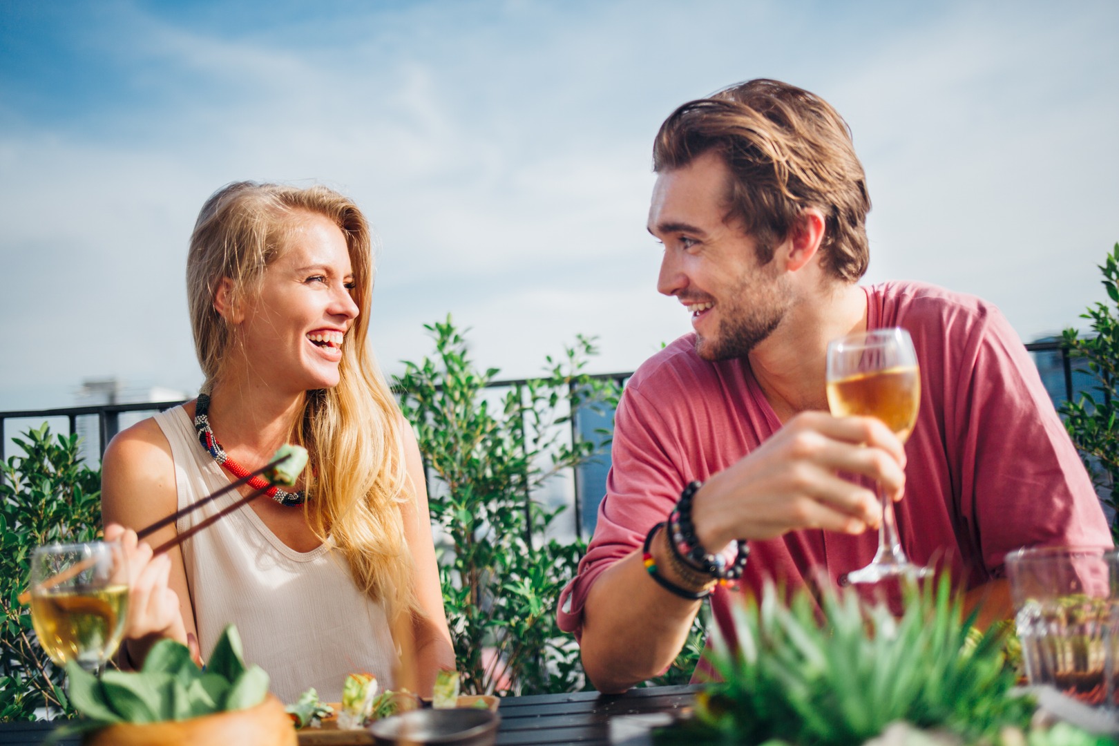 Two friends dining on a sunny terrace with drinks